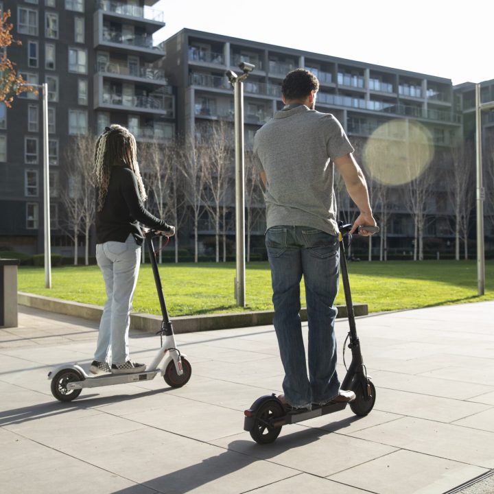 full shot people traveling with electric scooters